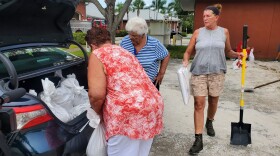 Residents in Bonita Springs, Karen Anderson (far left) and Kathleen Hanrahan (far right), load sandbags into the truck of their car at the Bonita Springs Fire Department Station 26.