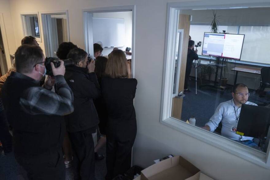 Brian Jackson, elections program manager for the Alaska Division of Elections, right, reviews the final count from his computer as media and other spectators watch in Juneau on Wednesday.