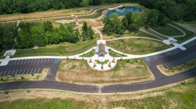 A areal shot of the Whalfield dog park, trees, grass, a pavilion, parking spaces, walking paths, and a pond.