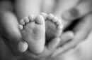Feet of a newborn baby in the hands of parents. Happy Family oncept. Mum and Dad hug their baby's legs.