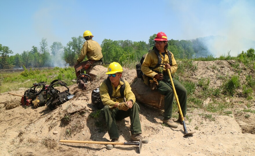 Firefighters from the U.S. Forest Service take a break from fighting a wildfire that scorched 2,400 acres of forest near Grayling on June 4, 2023.