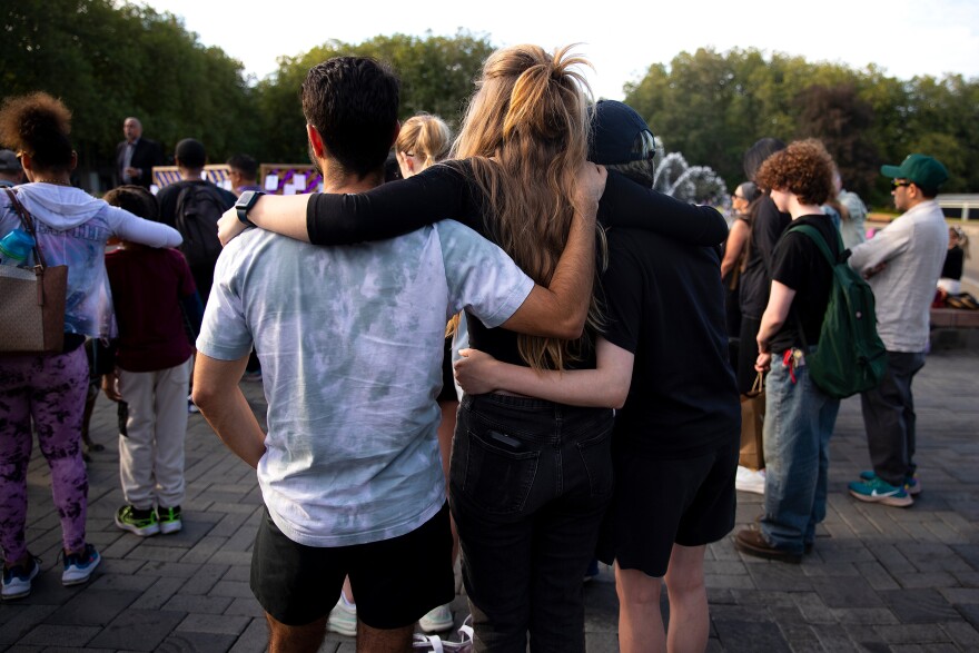 People stand arm-in-arm in a crowd.