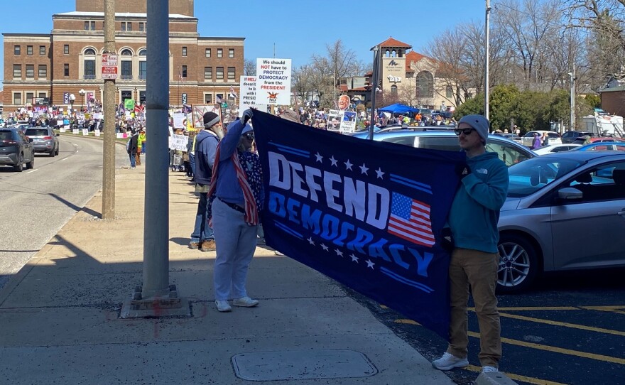 Protesters hold a banner that reads "Defend Democracy" at the Bloomington "No kings" protest.