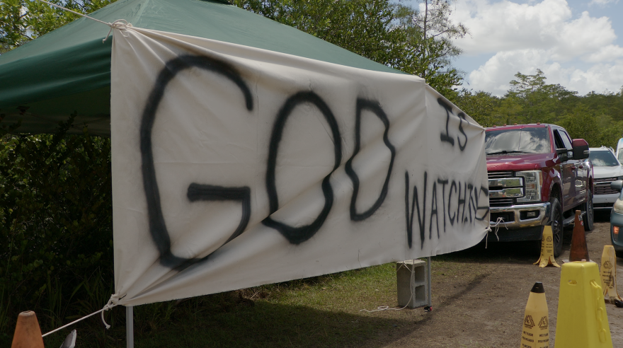 A banner advising "God Is Watching" greeted those who attended a prayer gathering Saturday at the entrance to the Everglades detention center off U.S. 41 near Ochopee.