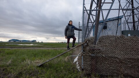 Seth Friend, 12, stands at the base of a wind turbine in Kwigillingok last month. Grass tangled in the fence marks the height reached by floodwaters from ex-typhoon Halong.