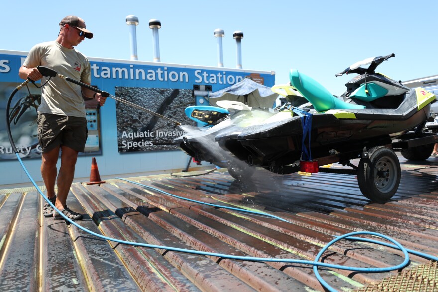 A DNR worker hoses down a jet ski after it was pulled from a Utah reservoir.
