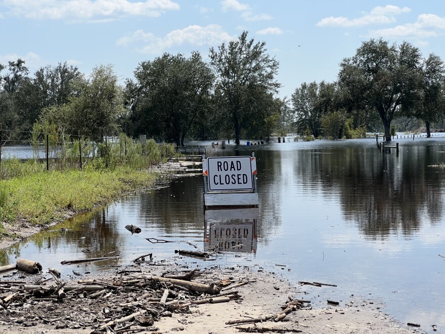 A sign that says "Road Closed" on a road that is flooded with water