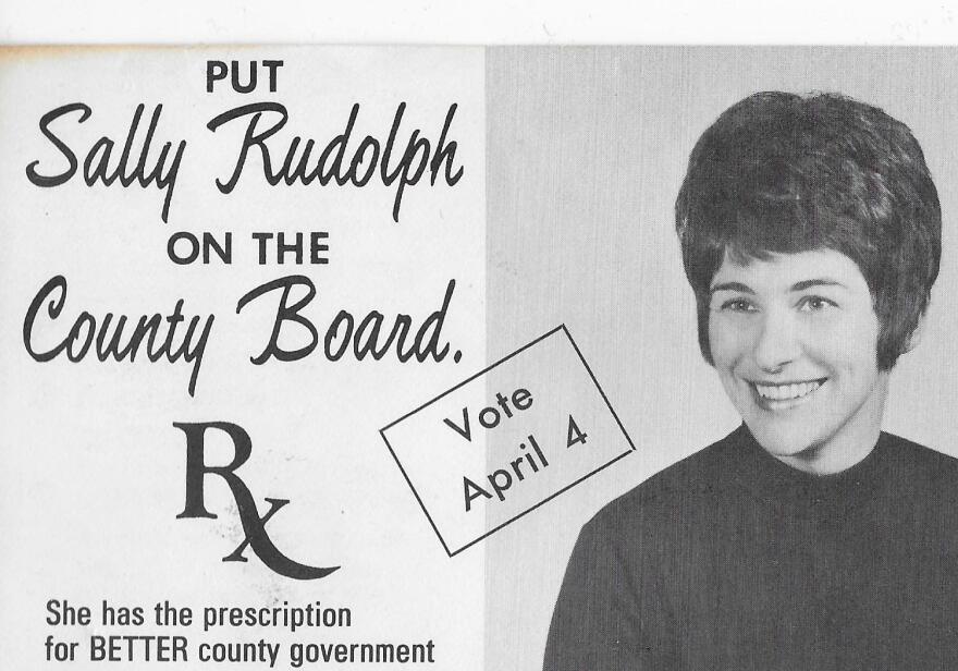 Black-and-white campaign ad with a photo of a smiling woman. Text reads: "Put Sally Rudolph on the County Board. She has the prescription for BETTER county government. Vote April 4.