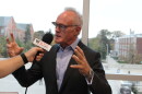 A man talks and gestures in front of a microphone 