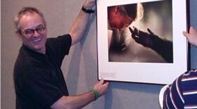 National Geographic photographer Nick Nichols stands with one of his photos.
