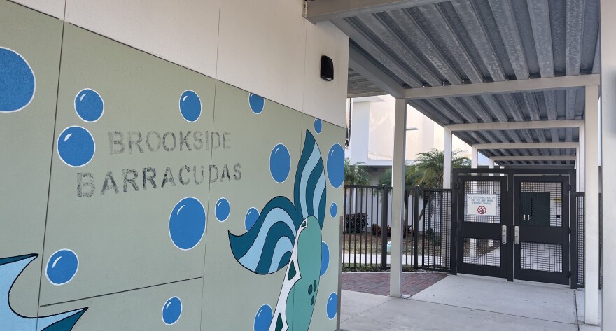 A fading sign says "Brookside Barracudas" on a middle school building.