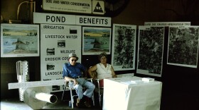 A man and a woman sit at a booth for the Hamilton County Conservation District.