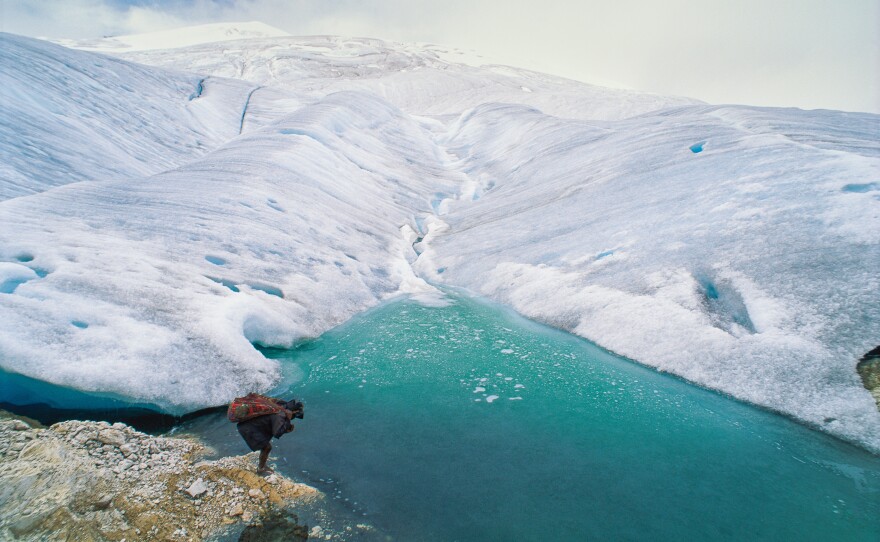 A barefoot porter totes a load for an expedition visiting one of the remaining glaciers near the equator, 16,000 feet high on the highest peak in Papua, Indonesia.