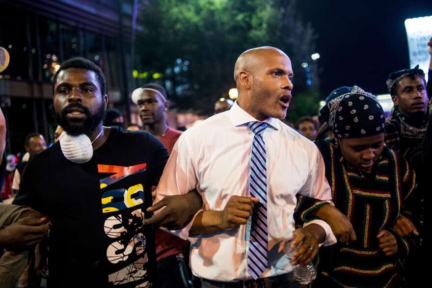 Protesters, including public defender Toussaint Romain (center), march in the early hours of Friday in Charlotte, N.C. Despite a midnight curfew, police allowed the peaceful march to continue without interference. Protests began on Tuesday night following the fatal shooting of 43-year-old Keith Lamont Scott.