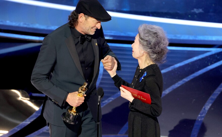 Troy Kotsur accepts the Actor in a Supporting Role award for "CODA" from Youn Yuh-jung onstage.