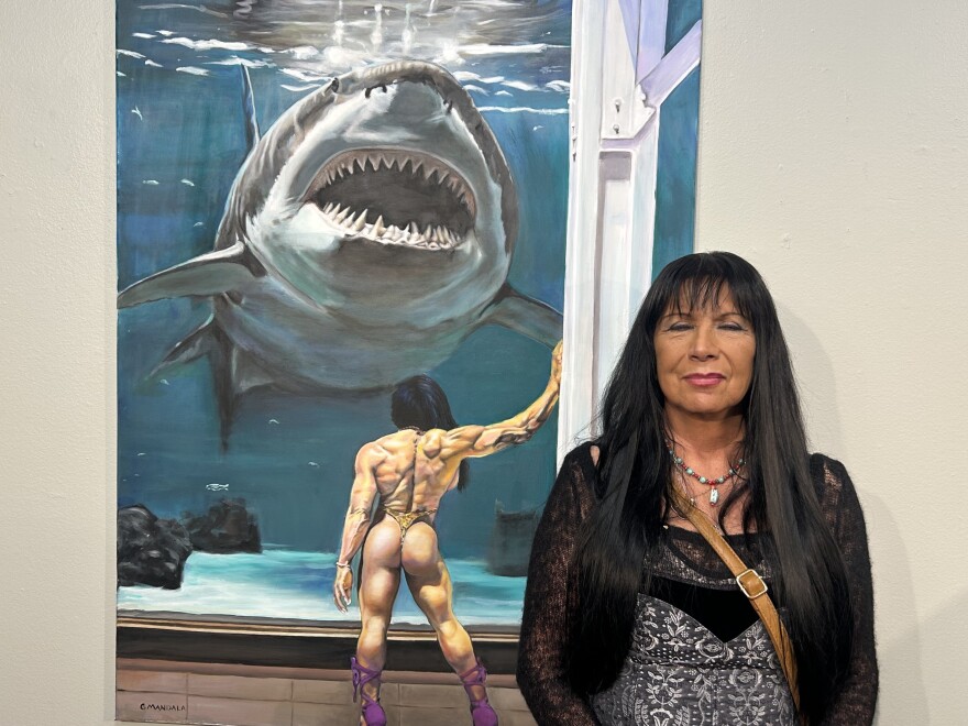 Artist Gloria Mandala poses for a portrait next to her painting, "The Conversation"