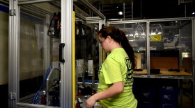 A worker at a factory in North Vernon, Indiana, works with a plastics manufacturing robot.