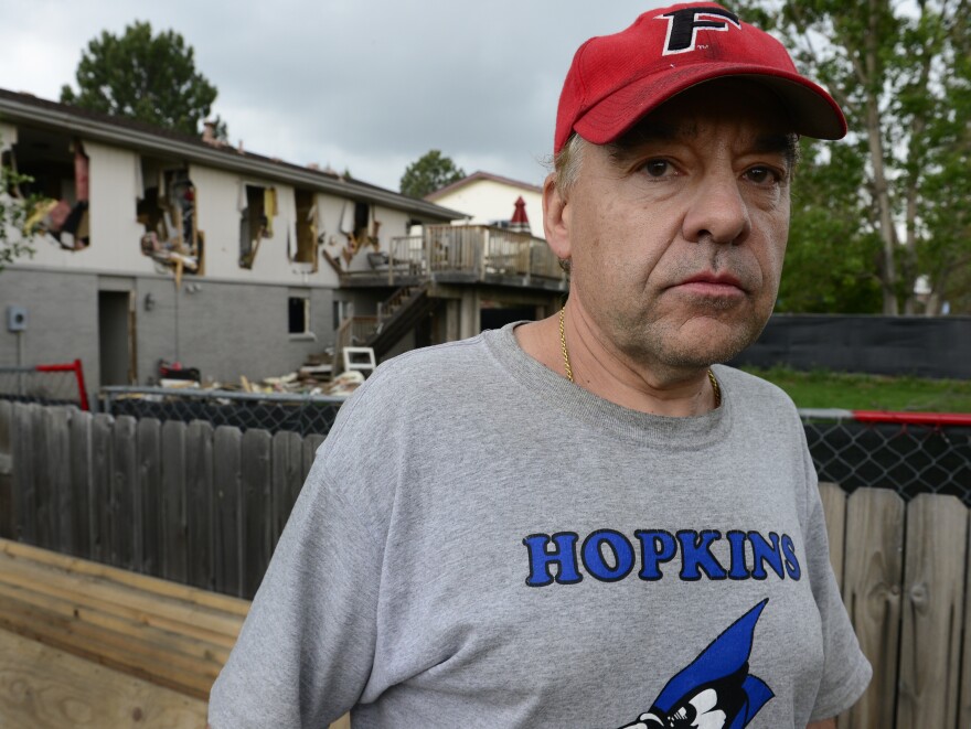 Leo Lech stands on a pile of wood in his neighbor's yard, which overlooks the back of his former home in Greenwood Village, Colo. In 2015, the home was destroyed by the police during a standoff with a gunman and has since been razed and rebuilt. On Tuesday, a federal appeals court ruled that the city does not owe Lech any compensation.