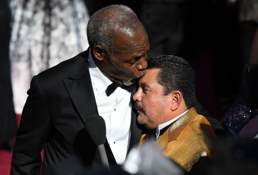 Actor Danny Glover kisses TV host Guillermo on the head.