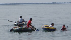 Students maneuver rafts to the GPS coordinates of the sunken scow W.R. Hanna while others look underwater to find it.