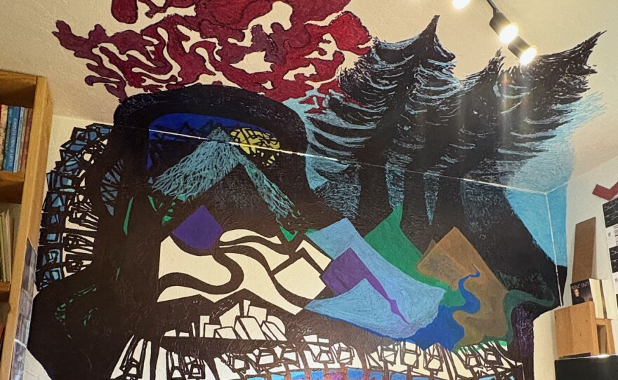 A mural of an abstract piano with mountains and trees on a white wall. 