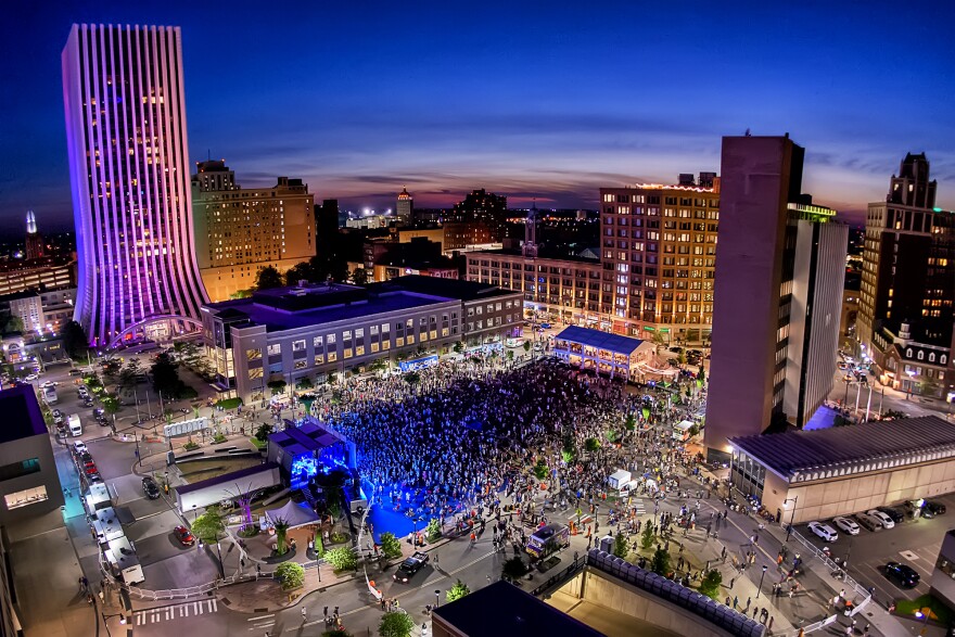 An aerial view of Parcel 5 at night. A large crowd of Jazz Fest attendees are in the center.