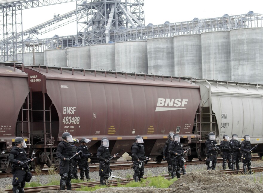 Police in riot gear protect an incoming train carrying grain at the port facilities in Longview, Wash., on Wednesday..