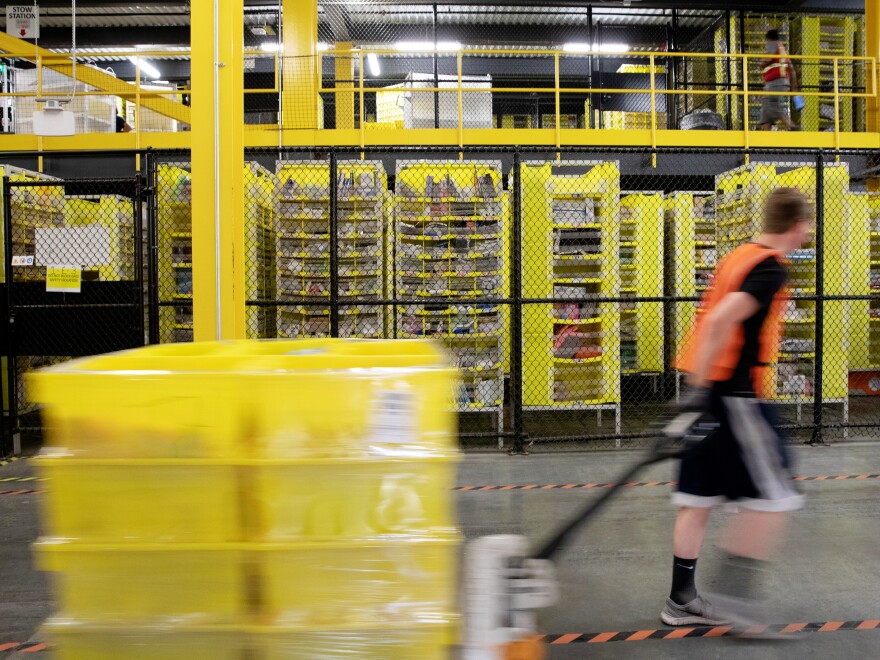 A worker pulls a pallet jack with plastic crates at an Amazon warehouse in New Jersey. The company is facing its biggest labor battle yet with a unionization vote expected at a facility in Alabama.