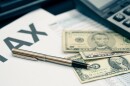 Tax season concept. Tax planning and consulting service business. Pen, calculator, dollar banknote, and income tax return form for filling and calculating tax payments. Money and financial concept.