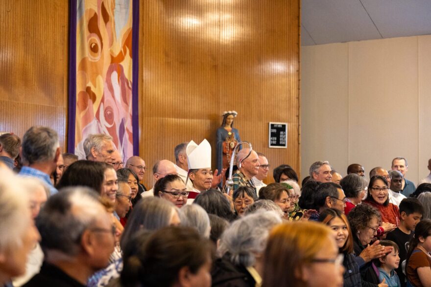 Bishop of the Diocese of Fairbanks, Steven Maekawa, stands in the middle of a crowd waiting to take a photo at Bethel's Immaculate Conception Church.