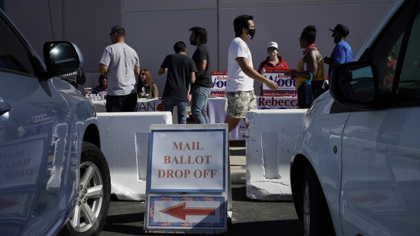 A sign indicates where mail ballots may be dropped off as people wait in line at one of a few in-person voting places during a nearly all-mail primary election in Las Vegas in a 2020 file photo.