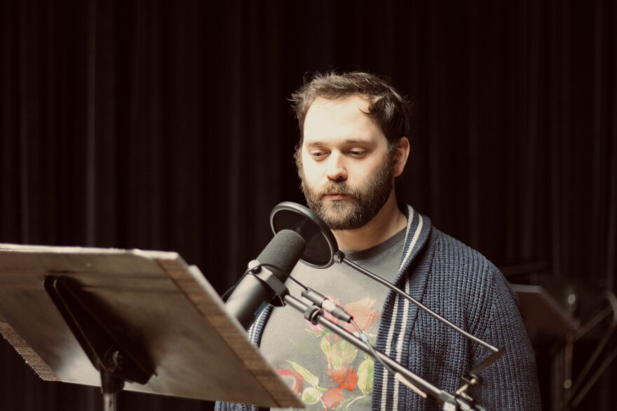Man talks in front of a mic and podium.