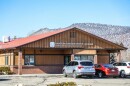 The exterior of a post office building with a few cars parked outside.