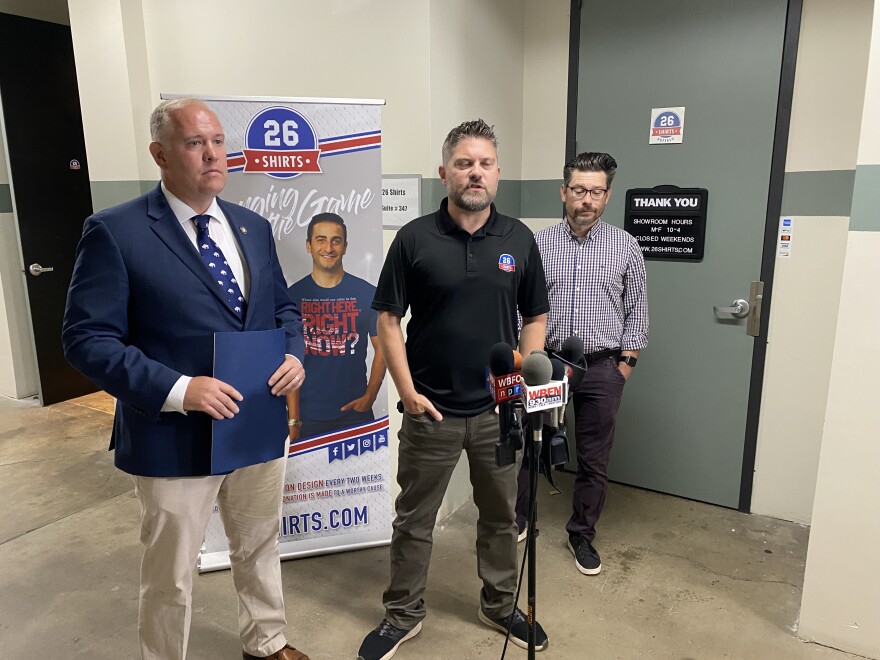 NYS Assemblyman Bill Conrad stands with 26 Shirts Co-Owners Del Reid and Dan Gigante