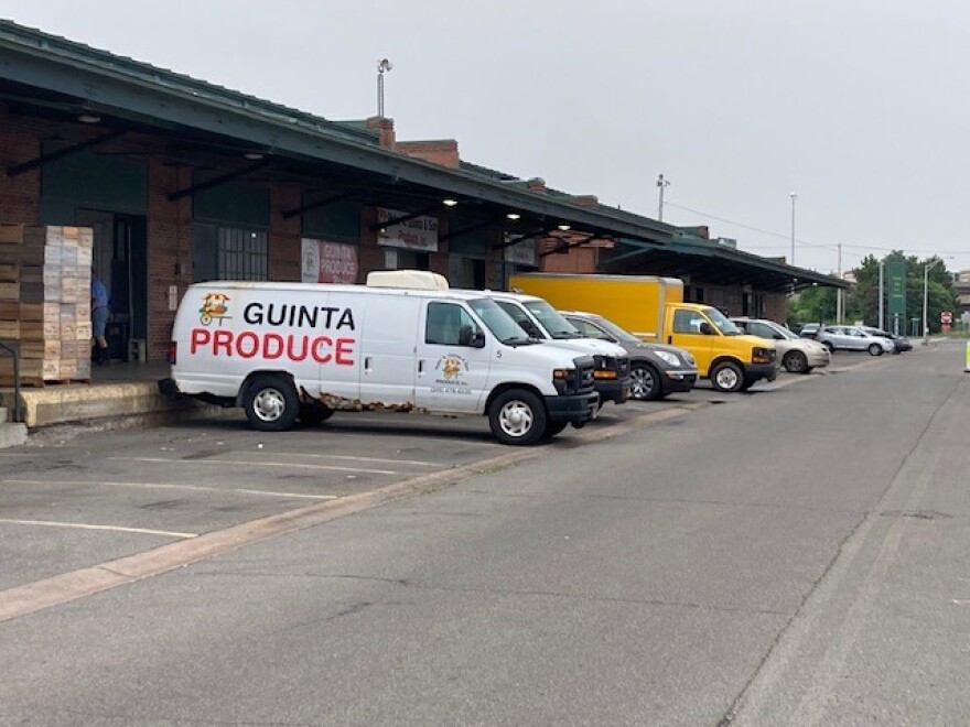 Trucks and vans are backed up to a loading docs of an old building.