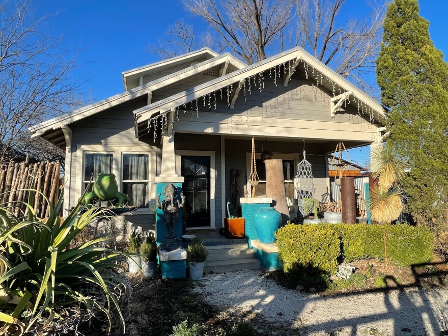 A grey one-story house has lights hanging from the roof.