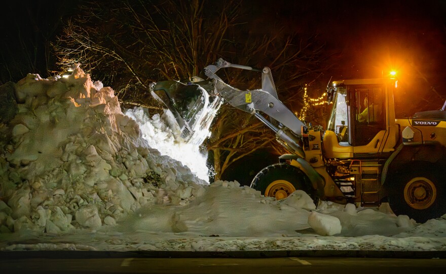 On Sunday evening, as flakes from the coming storm began to fall, a hill of snow from last month's accumulation is made higher by snow removal equipment at E.O. Smith High School in Mansfield, Ct. Forecasters are predicting more than a foot of snow will fall through Monday with wind gusts as high as 55 mph.