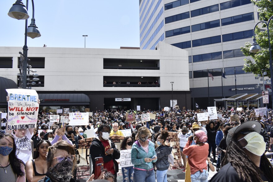 A crowd of protestors standing together and holding signs.