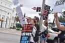 People stand along South Orange Avenue in downtown Orlando on Saturday, holding signs as passing drivers honk in response during the No Kings Day rally.