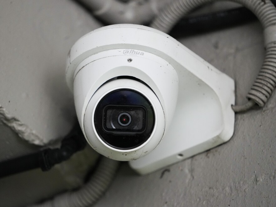 Close up of a white security camera mountain on what appears to be an exterior concrete wall.