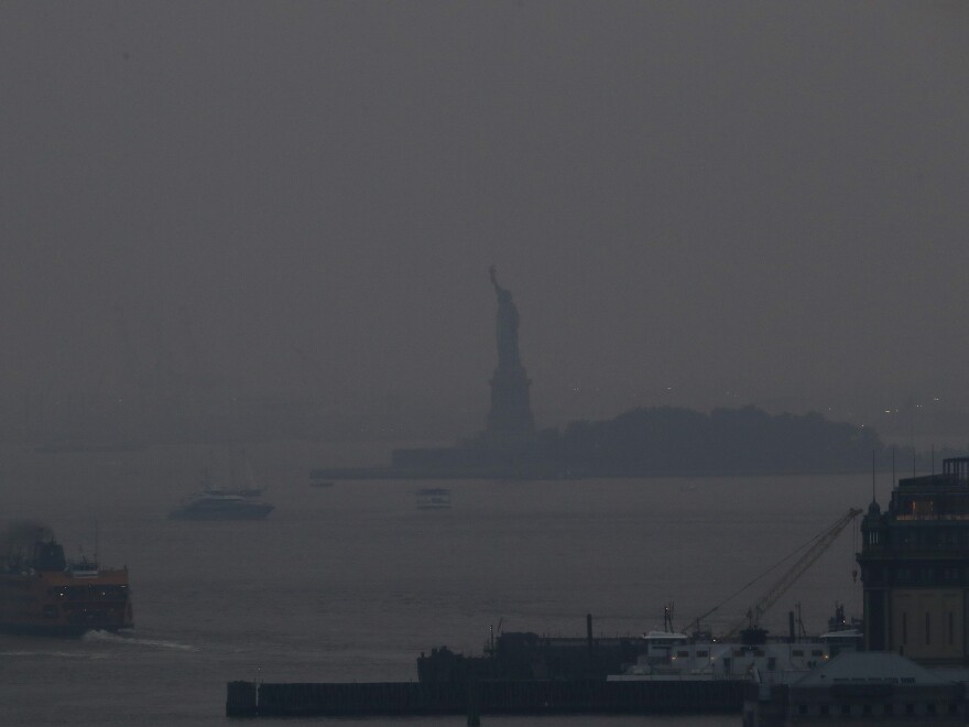 The Staten Island Ferry departs from the Manhattan terminal through a haze of smoke from Western wildfires, with the Statue of Liberty barely visible on July 20.