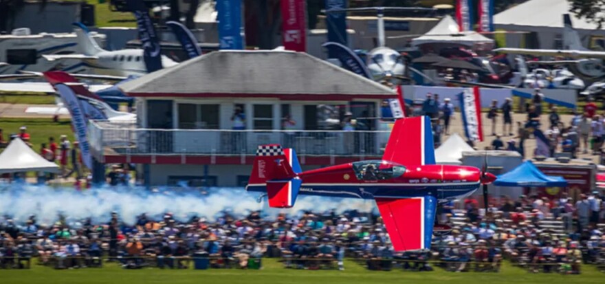 Red airplane flies over crowd 