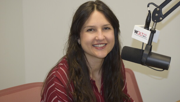 A woman sits in front of a microphone and smiles 