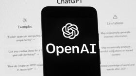 The OpenAI logo is seen on a mobile phone in front of a computer screen which displays the ChatGPT home Screen, Friday, March 17, 2023, in Boston.