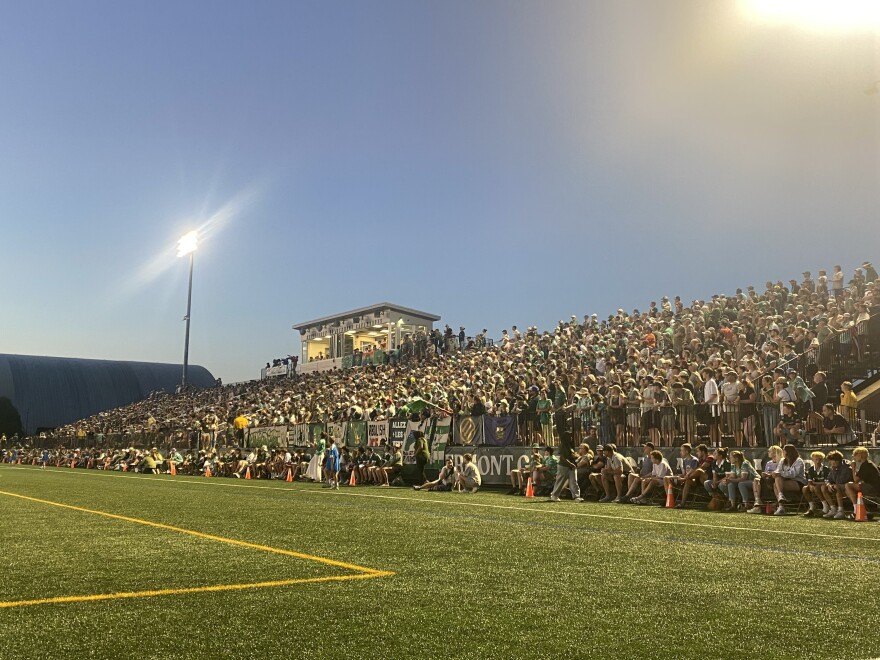 A crowd stands in the bleachers at Virtue Field to watch the Vermont Green soccer match.