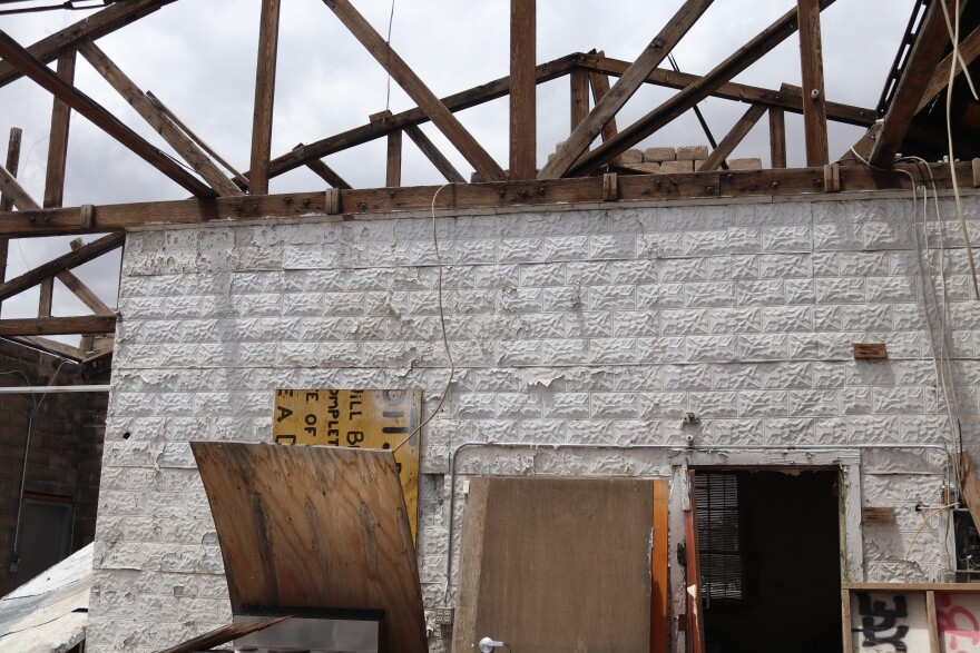  A brick wall with peeling white paint supports rafters that open to the sky