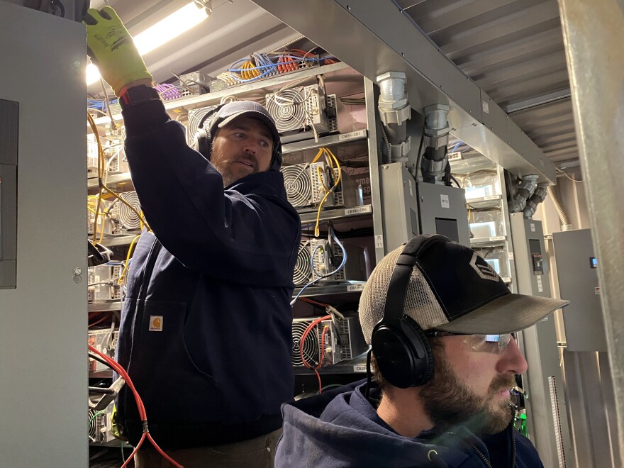 Workers install cryptocurrency mining computers inside a converted shipping container at the Compute North facility in Nebraska. [John Ruwitch / NPR]