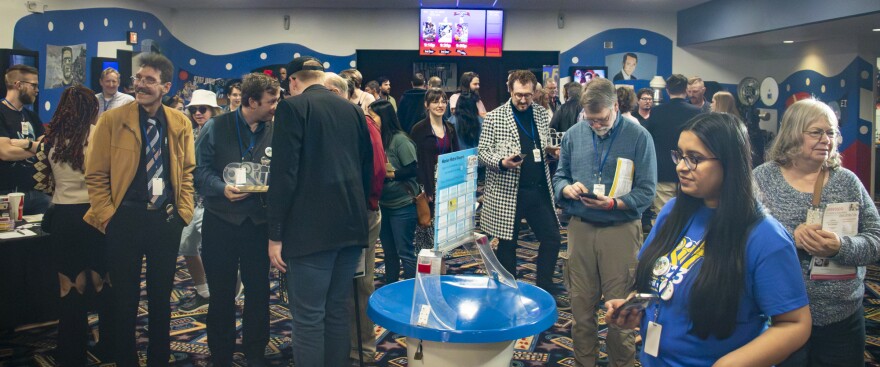 The lobby of a movie theater is crowded with people attending a film festival.