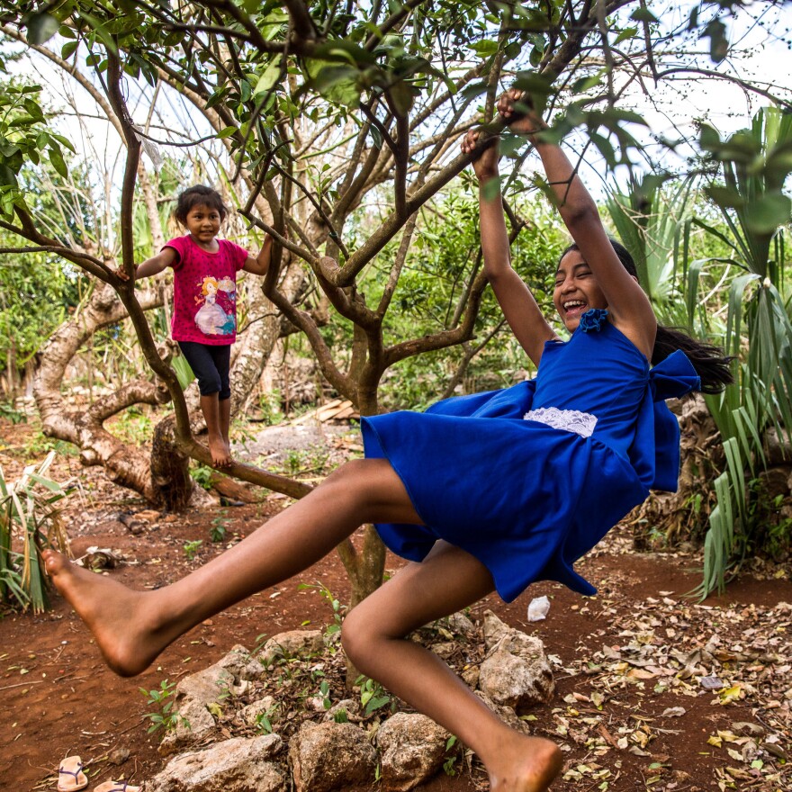 Gelmy, 9, and sister Alexa, 4, climbing trees in the backyard of their family home in the Yucatan Peninsula.