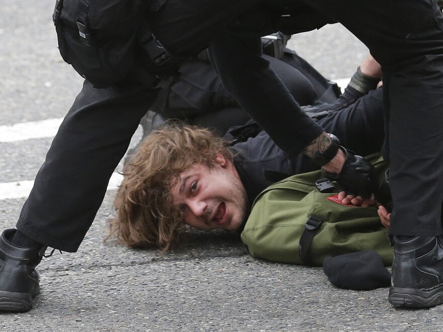 Police officers arrest a man during a May Day march, on Friday, in Seattle.